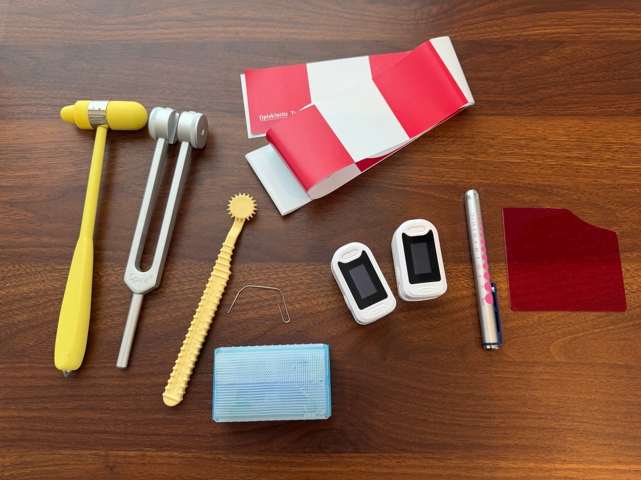 神経学的検査で使用する器具一式。打診器、音叉、感覚検査用のルーレット・クリップ・感覚ブラシ、パルスオキシメーター、ペンライト、赤フィルター、視運動性刺激テープ